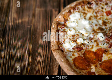 Composite-assorted pizza on a natural wooden surface of pine boards. Daylight. Close-up. Free space to sign. Shallow depth of field. Stock Photo