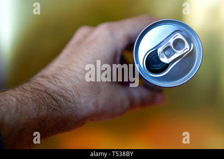 Male hand holding an open aluminum can of drink. View from above. Shallow depth of field. Stock Photo