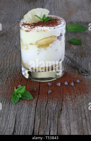 Concept of italian dessert. Pineapple Tiramisu in a glass cup on wooden table. Closeup Stock Photo