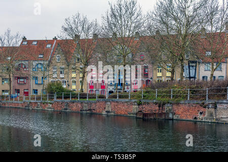 Old street of Bruges with colorful medieval houses standing along the canal with bright windows and doors. Cityscape of Bruges streets. Stock Photo