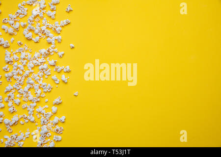 Fresh salty pop corn scattered on yellow color background, copy space, top view Stock Photo