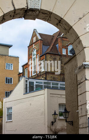 Brick multi-level house with large beautiful windows. Picture taken through the old arch. Central London. Stock Photo