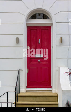 Red Wooden Entrance Door to residential building in London. Typical door in the English style. Stock Photo