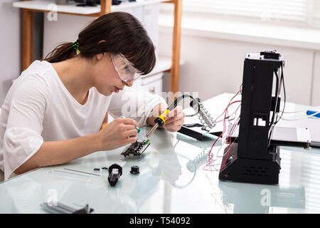 Female Engineer Or Tech Repairs Electronic Device In Hardware Repair Shop Stock Photo