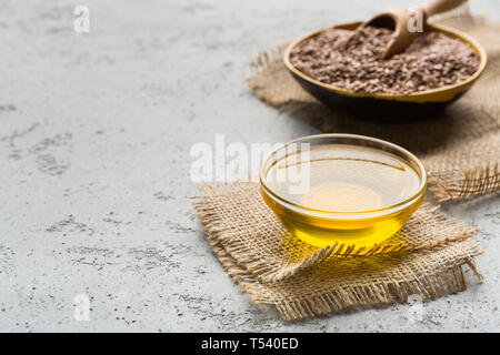 Linseed oil, bowl and scoop of linseeds on concrete background, copy space. Natural medicine concept Stock Photo