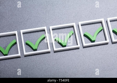 An Overhead View Of Green Check Marks Sign Arranged White Blocks Against Gray Background Stock Photo