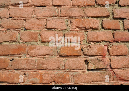 Old flaky red brick wall with cracks and scratches Stock Photo