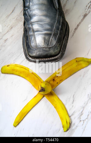 Business man stepping on comedy slippery banana peel Stock Photo