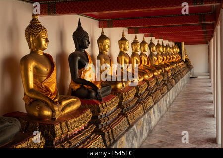 Thailand, Bangkok, Wat Pho, outer Phra Rabiang of Phra Ubosot, line of golden Buddha statues with one black figure Stock Photo