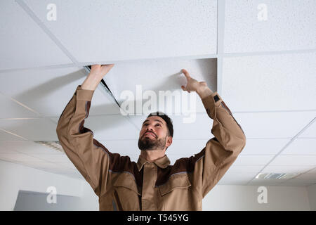 Close-up Of Young Electrician Repairing Ceiling In Office Stock Photo
