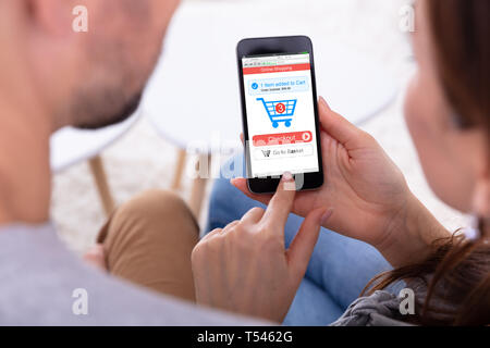 Close-up Of Couple Using Online Shopping Application On Mobile Phone Stock Photo