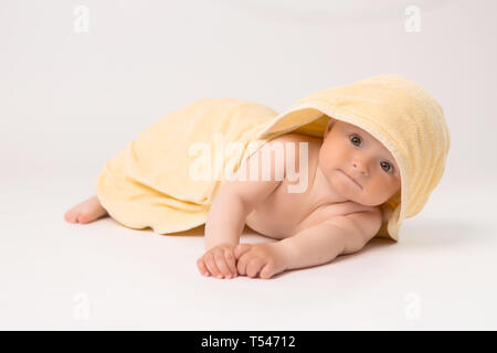 toddler boy with yellow towel on head on white background, Portrait of cute Caucasian newborn baby. The child is wrapped in a yellow soft towel after Stock Photo