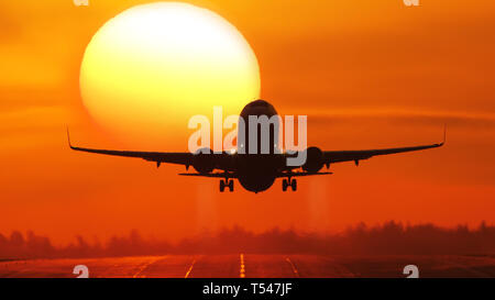 Airliner taking off at sunrise, passing the sun Stock Photo