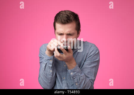 young man standing, using smartphone and watching video with amazed face. Stock Photo