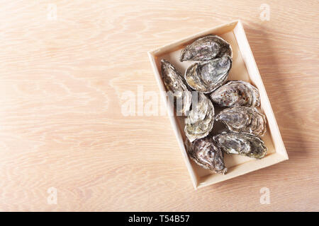Oysters on box on wooden background, toned image. Shellfish contains a mass of beneficial micronutrients and vitamins that beneficially affect the ent Stock Photo