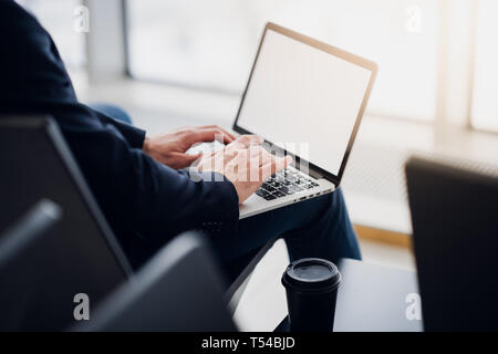 Business man hands on a laptop using wi-fi internet in airport. Close-up of a man's hands typing message on a keyboard, browsing the worldwide web Stock Photo
