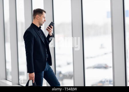 Concentrated businessman recording voice message at airport Stock Photo
