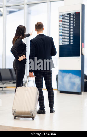 Business couple looking at the timetable holding boarding pass at the airport Stock Photo