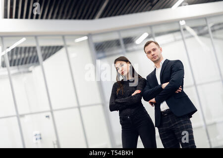 A business man and woman standing back to back with smiles on their faces Stock Photo