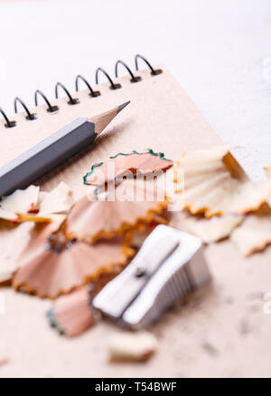 A notebook, a sharpener, shavings and pencils on a white background.Drawing with pencils. selective focus Stock Photo