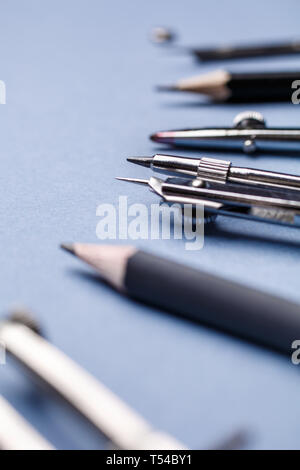 The compass, along with other tools for drawing on the blue background. The set of elements reflecting the concept of engineering and design. selectiv Stock Photo