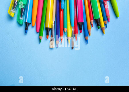 Colored pens, pencils, markers and other objects lie on a light blue background. Concept of education or back to school. Top view, flat lay. copyspace
