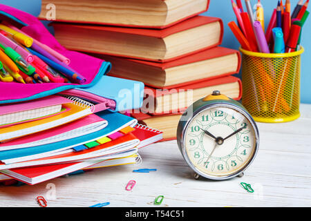 Composition lined with colorful school stationery. At 10 o'clock hour is time to study. Group of school supplies and books on wooden table Stock Photo