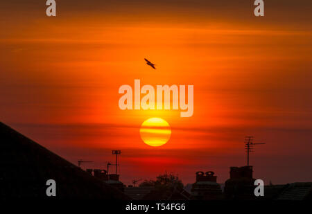 London, UK. 20th April, 2019. Sun sets over suburban rooftops in a clear orange sky after a day of cloudless skies and soaring summer temperatures during Easter holiday weekend. Credit: Malcolm Park/Alamy Live News. Stock Photo