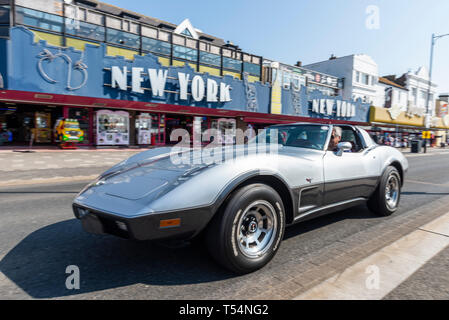 Classic car show taking place along the seafront at Marine Parade, Southend on Sea, Essex, UK. Chevrolet Corvette Stingray driving past New York amusement arcade Stock Photo