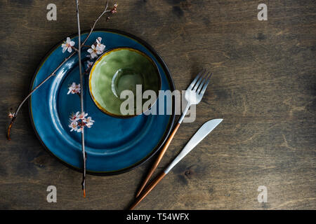 Spring table setting with peach blooming tree branch on wooden background with copy space Stock Photo