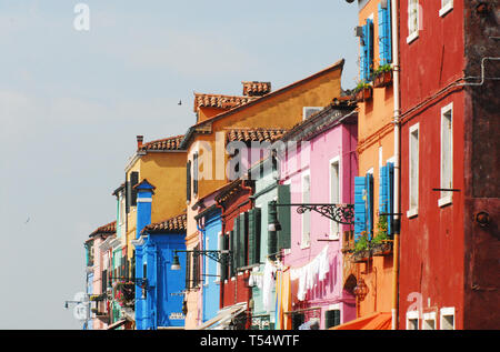 Beautifully contrasting colors of homes and shops on the island of Burano in the Venetian lagoon of Italy.  Note the space for your text in the clear  Stock Photo