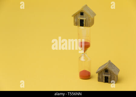 Real estate investment concept. Sand glass and miniature house Stock Photo