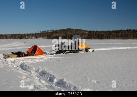 Snowmobile with a sled packed with fishing gear standing on the ice