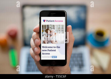 A man looks at his iPhone which displays the Patient Access logo (Editorial use only). Stock Photo