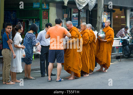 BANGKOK, THAILAND - DECEMBER 27, 2018: Buddhist monks collect food on a city street in the early morning Stock Photo