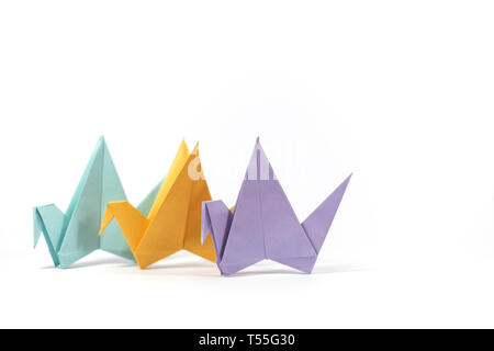 Three hand folded pastel coloured origami paper cranes, standing isolated on a white background Stock Photo