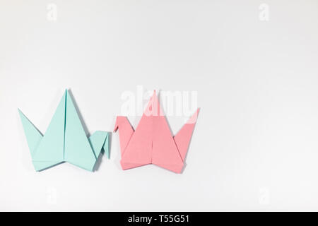 Two hand folded pastel coloured origami paper cranes facing each other, isolated on a white background Stock Photo