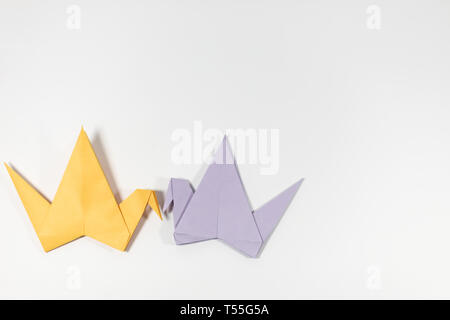 Two hand folded pastel coloured origami paper cranes facing each other, isolated on a white background Stock Photo