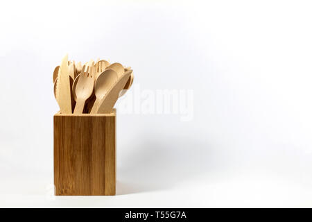 Wooden biodegradable utensils in a bamboo holder, set on a white background with copy space. Stock Photo