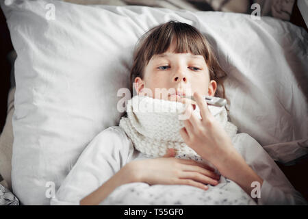 teenage girl with a cold measures the temperature Stock Photo