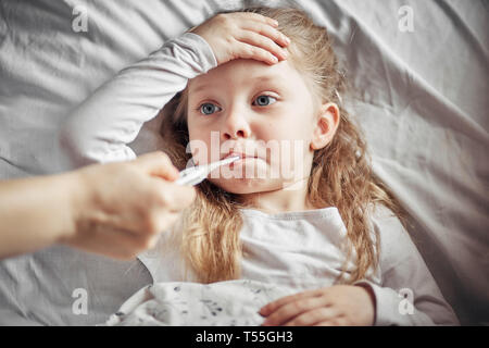 caring mother measures the temperature of a sick little girl