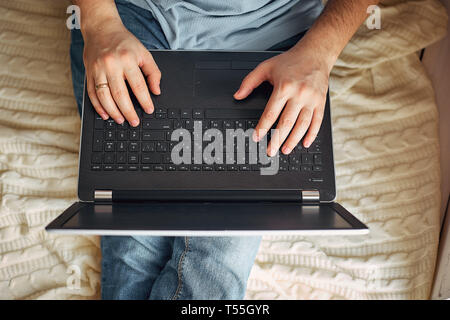Top view of male hands using modern laptop, close up of young man working at home and using notebook computer, man's hand using technology Stock Photo