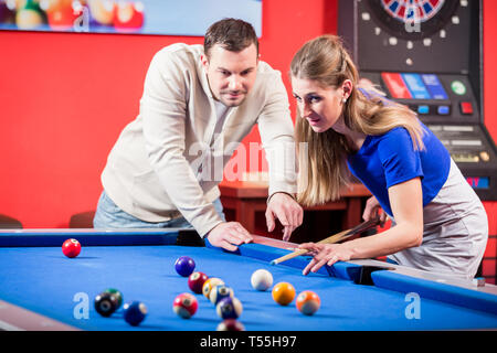 Woman receiving advice on shooting pool ball while playing billiards Stock Photo