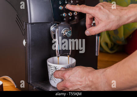 Two hands operate a coffee machine Stock Photo