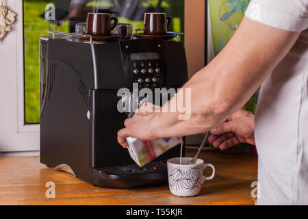 A hand pouring condensed milk in a cup of coffee Stock Photo