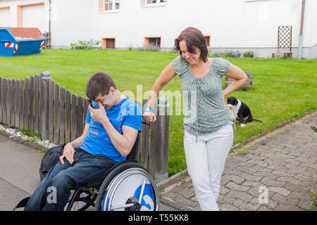 Mother with handicapped son waiting for the school bus Stock Photo