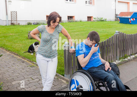 Mother with handicapped son waiting for the school bus Stock Photo