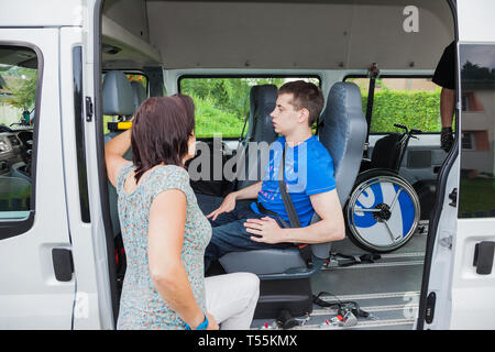 Handicapped boy is picked up by school bus Stock Photo