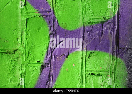 Lime-green and violet paints on the old brick wall, contrast background Stock Photo