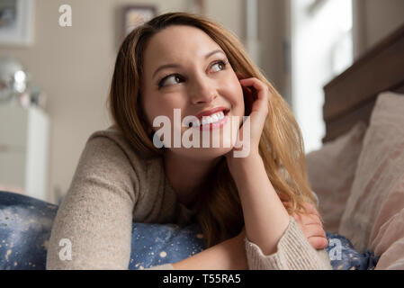 Young woman day dreaming on bed Stock Photo